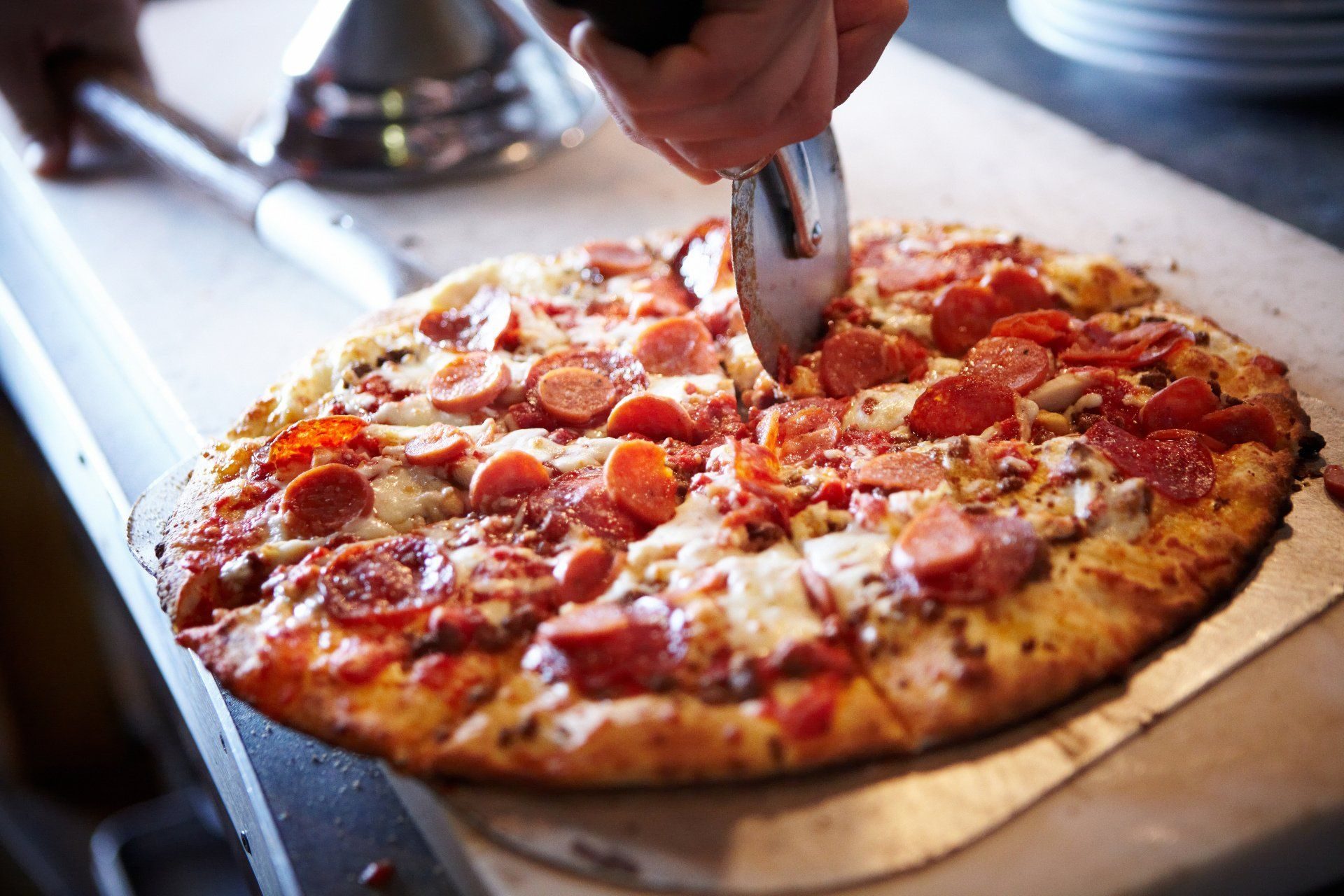 A fresh pepperoni pizza being sliced at Palasad